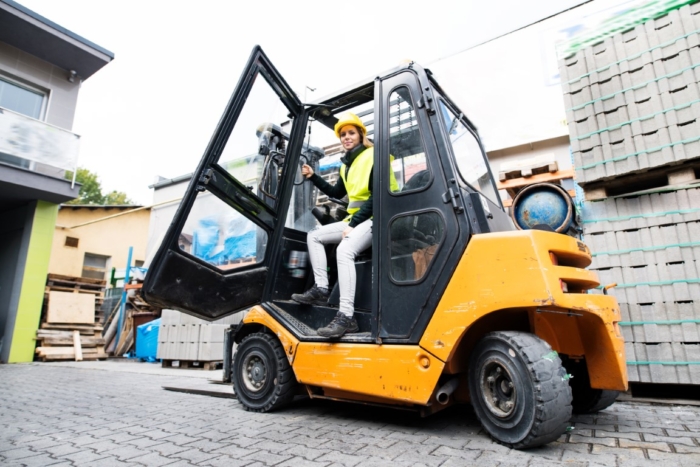 Female forklift truck driver outside a warehouse.